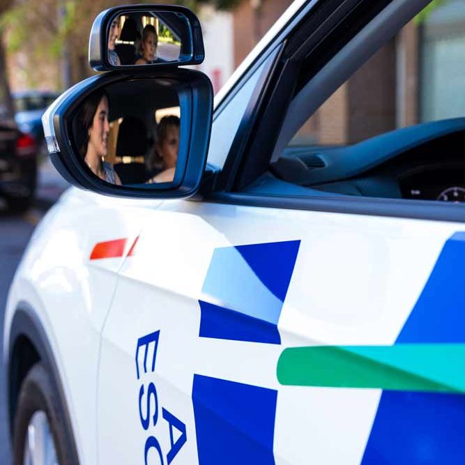 Retrovisor exterior de un coche de Autoescuela Vial con el reflejo de la alumna y la profesora